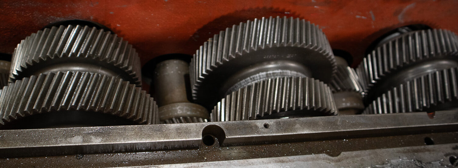Close-up view of industrial gearbox showing multiple interlocking steel gears, emphasizing heavy-duty gear system components and mechanical power transmission.