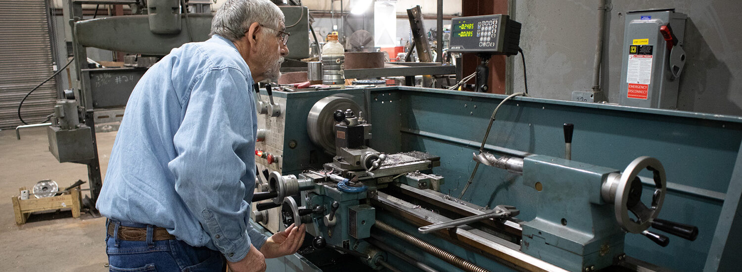 Experienced machinist operating a precision manual lathe in an industrial machine shop, showcasing hands-on metalworking, custom shaft repair, and electric motor component machining.